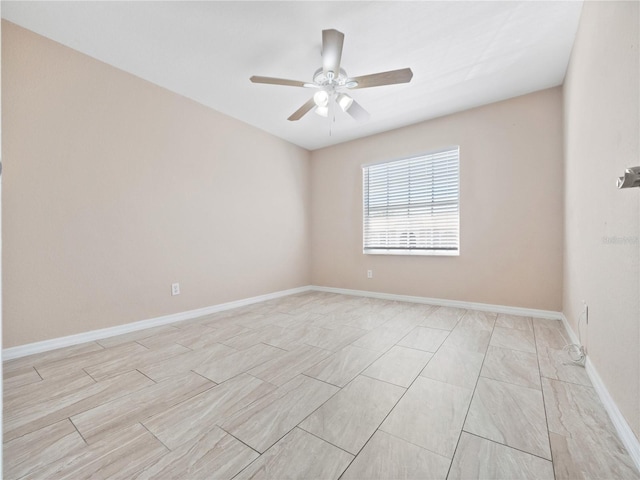 spare room with a ceiling fan and baseboards