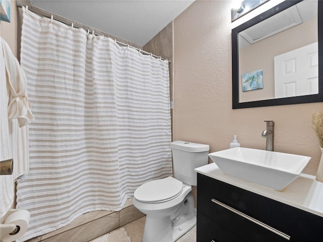 bathroom featuring toilet, tile patterned flooring, a shower with shower curtain, a textured wall, and vanity