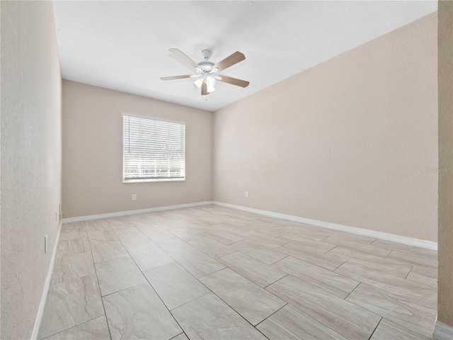 empty room featuring a ceiling fan and baseboards
