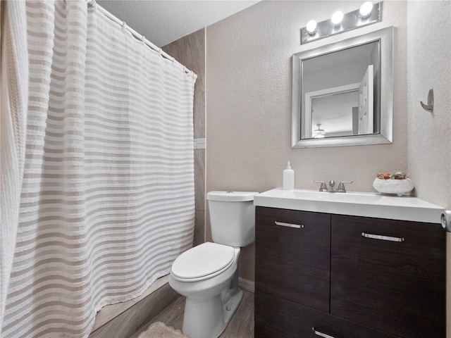 full bathroom featuring a textured wall, toilet, vanity, and a shower with curtain