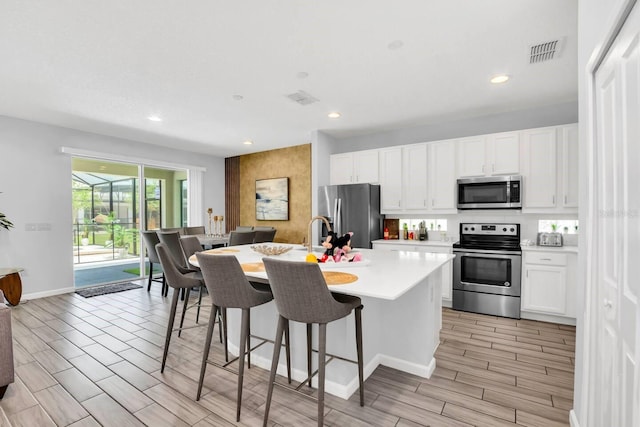 2616 Calistoga Ave, Kissimmee, FL 34741 - kitchen featuring wood tiled floor, a breakfast bar, light countertops, appliances with stainless steel finishes, and visible vents