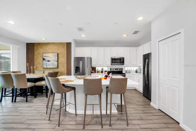 2616 Calistoga Ave, Kissimmee, FL 34741 - kitchen featuring wood tiled floor, visible vents, a kitchen bar, and appliances with stainless steel finishes