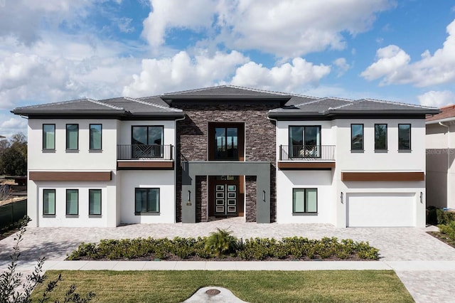 view of front of home featuring stucco siding, decorative driveway, stone siding, and a garage
