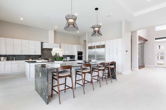 kitchen with stainless steel appliances, a large island, decorative backsplash, a high ceiling, and a breakfast bar