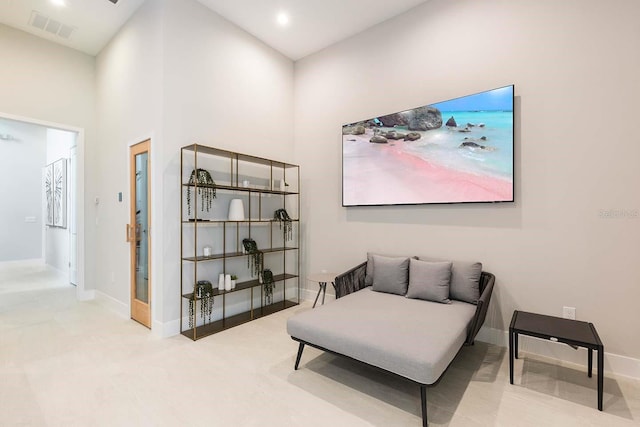 living area featuring visible vents, a towering ceiling, and baseboards