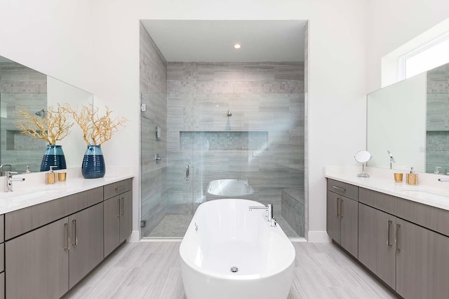 bathroom with a freestanding bath, two vanities, a sink, and a stall shower