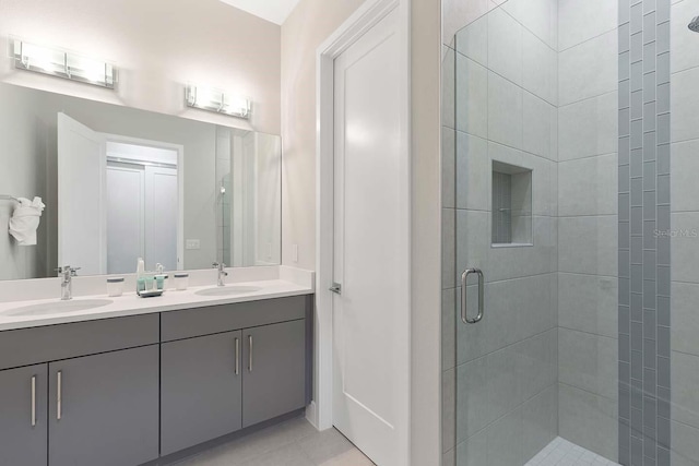 bathroom featuring tile patterned floors, a sink, double vanity, and a stall shower