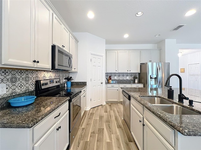865 Bay Bridge Cir, Apopka, FL 32703 - kitchen featuring stainless steel appliances, a sink, light wood finished floors, decorative backsplash, and an island with sink