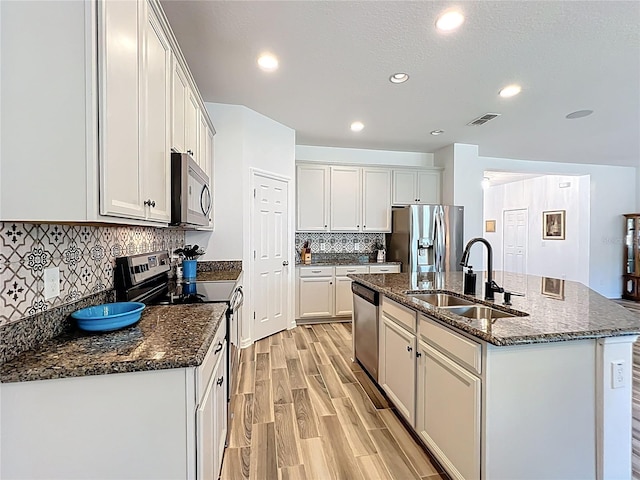 865 Bay Bridge Cir, Apopka, FL 32703 - kitchen featuring appliances with stainless steel finishes, a sink, an island with sink, tasteful backsplash, and light wood finished floors