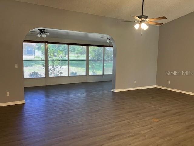 6419 Borg St, Leesburg, FL 34748 - unfurnished living room featuring a ceiling fan, baseboards, arched walkways, and dark wood-style flooring
