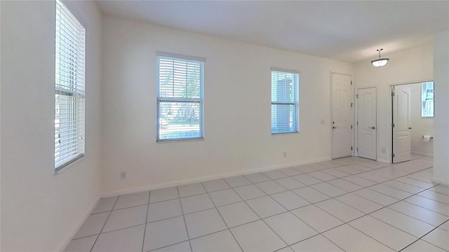 spare room with a wealth of natural light, baseboards, and light tile patterned floors