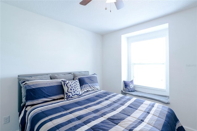 bedroom with baseboards, a ceiling fan, and a textured ceiling