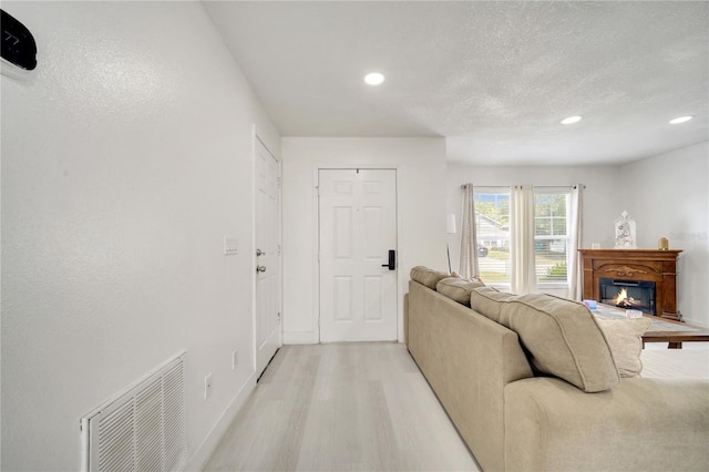 5118 Luna Negra Dr, Orlando, FL 32811 - living room with a glass covered fireplace, light wood finished floors, visible vents, and recessed lighting