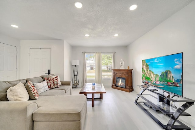 5118 Luna Negra Dr, Orlando, FL 32811 - living room with light wood-style flooring, a glass covered fireplace, a textured ceiling, and recessed lighting