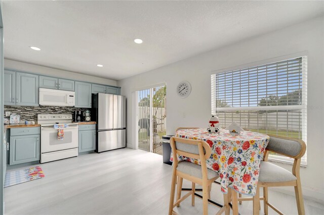 5118 Luna Negra Dr, Orlando, FL 32811 - kitchen featuring light wood finished floors, recessed lighting, backsplash, white appliances, and butcher block counters