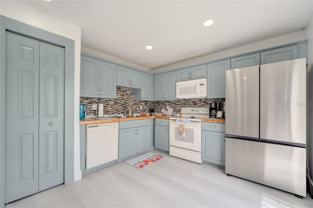 5118 Luna Negra Dr, Orlando, FL 32811 - kitchen with butcher block counters, white appliances, a sink, and tasteful backsplash