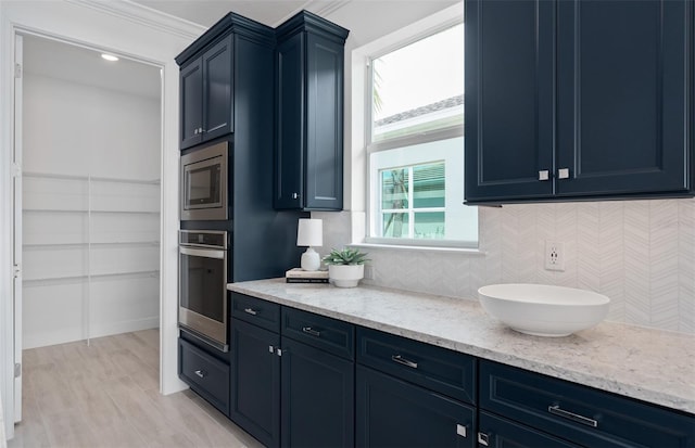 2725 Serenity Meadow Dr, Kissimmee, FL 34744 - kitchen featuring blue cabinetry, light stone counters, backsplash, ornamental molding, and appliances with stainless steel finishes