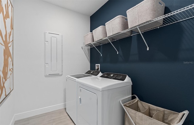 2725 Serenity Meadow Dr, Kissimmee, FL 34744 - laundry room featuring electric panel, light wood-style flooring, baseboards, laundry area, and independent washer and dryer
