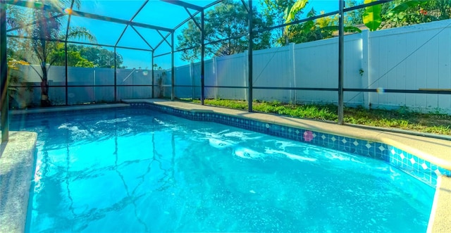 view of swimming pool featuring a fenced backyard, glass enclosure, and a fenced in pool