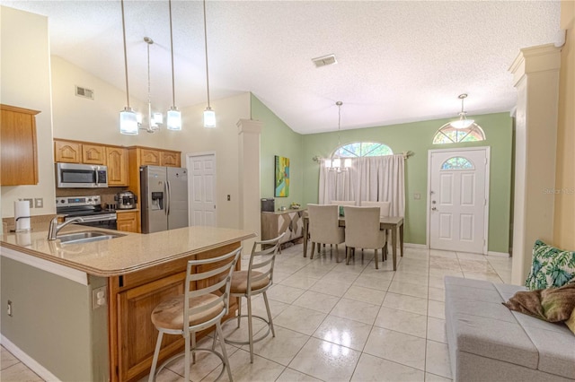 kitchen with stainless steel appliances, a sink, vaulted ceiling, visible vents, and a kitchen bar