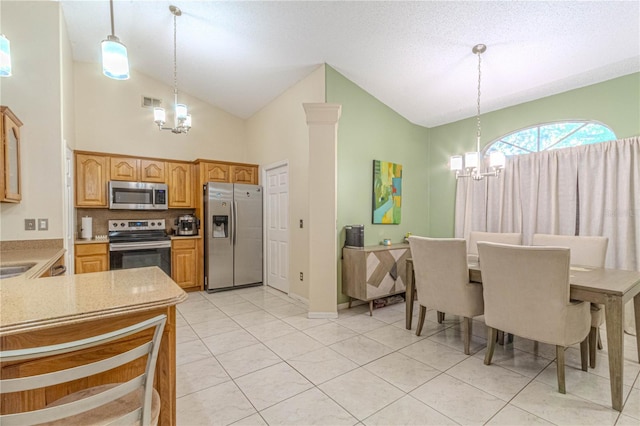 kitchen featuring light countertops, a chandelier, hanging light fixtures, appliances with stainless steel finishes, and high vaulted ceiling