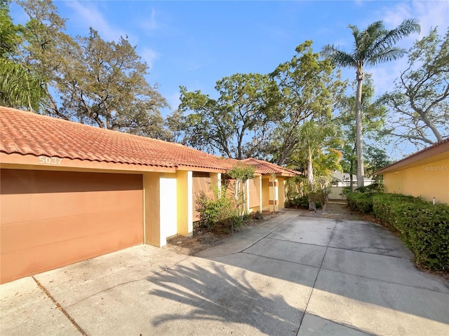 5037 Bermuda Cir Unit 10, Orlando, FL 32808 - view of side of property with stucco siding, a tile roof, driveway, and a garage