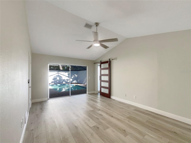 5037 Bermuda Cir Unit 10, Orlando, FL 32808 - empty room featuring a barn door, light wood-type flooring, vaulted ceiling, visible vents, and ceiling fan