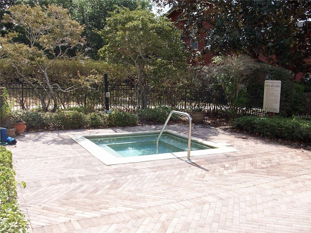 view of pool featuring fence and a hot tub