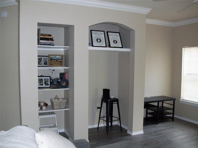 interior space with ornamental molding, built in shelves, wood finished floors, and baseboards