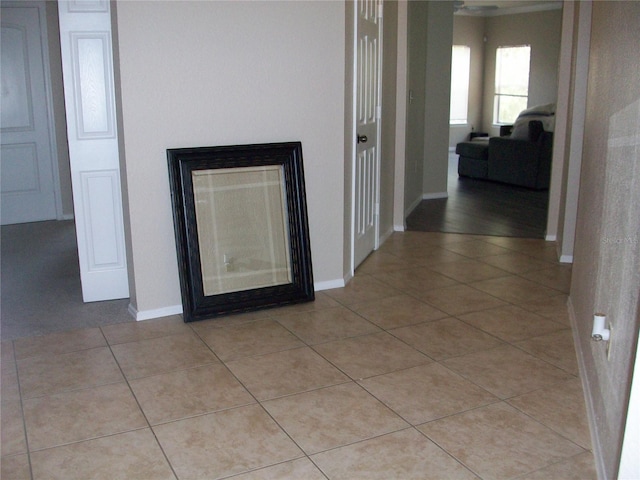 corridor featuring baseboards and light tile patterned flooring