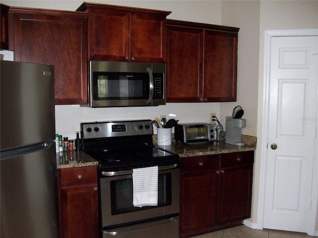 kitchen featuring a toaster, stone counters, reddish brown cabinets, and appliances with stainless steel finishes