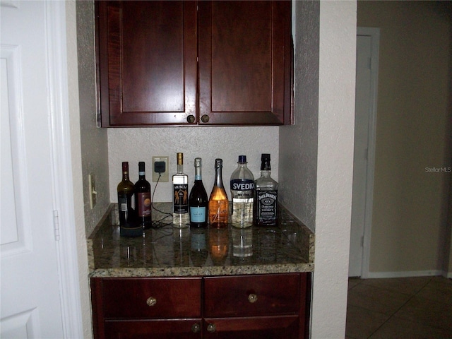 bar featuring a textured wall, tasteful backsplash, a bar, and tile patterned flooring