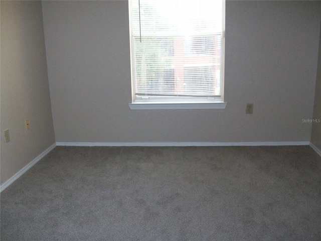 carpeted empty room featuring baseboards