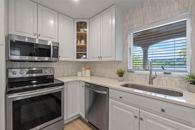1105 Lake Nettie Dr, Eustis, FL 32726 - kitchen featuring stainless steel appliances, decorative backsplash, white cabinetry, glass insert cabinets, and light countertops