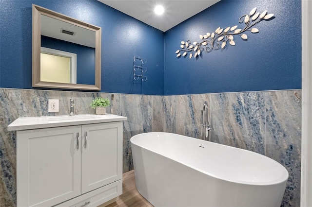 1105 Lake Nettie Dr, Eustis, FL 32726 - full bath featuring tile walls, a freestanding tub, wood finished floors, vanity, and a textured wall