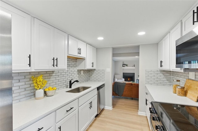 2716 Herrick Dr, Jacksonville, FL 32211 - kitchen featuring white cabinets, stainless steel appliances, a sink, light wood-type flooring, and light countertops