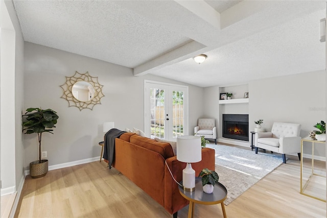 2716 Herrick Dr, Jacksonville, FL 32211 - living room with french doors, a textured ceiling, vaulted ceiling with beams, light wood-style floors, and a lit fireplace