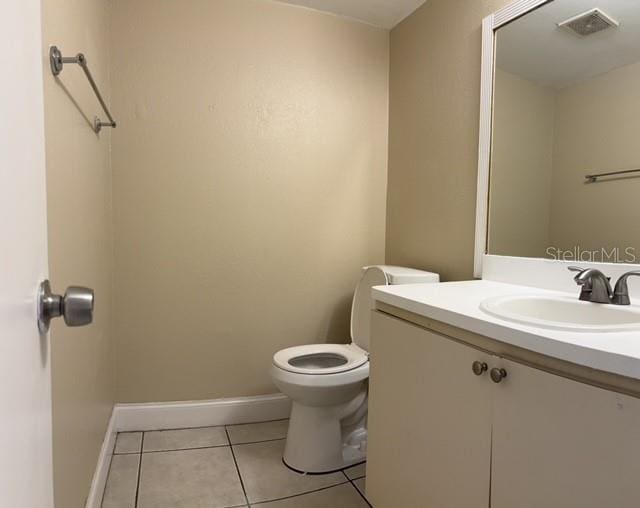 half bath featuring toilet, visible vents, baseboards, tile patterned flooring, and vanity