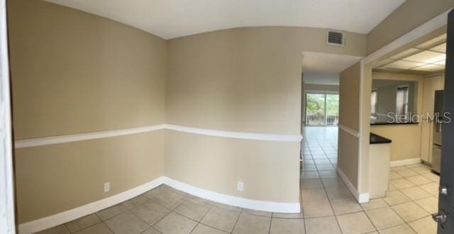 spare room featuring baseboards, light tile patterned flooring, and visible vents