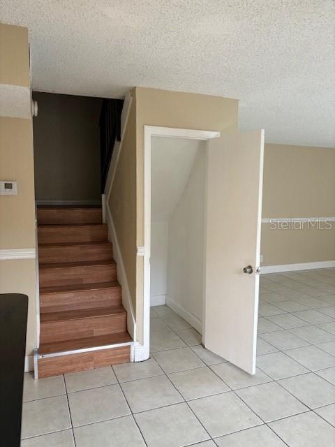 stairs featuring tile patterned floors and a textured ceiling