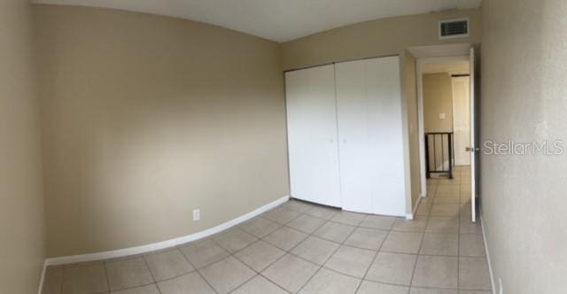 unfurnished bedroom with a closet, visible vents, baseboards, and light tile patterned floors