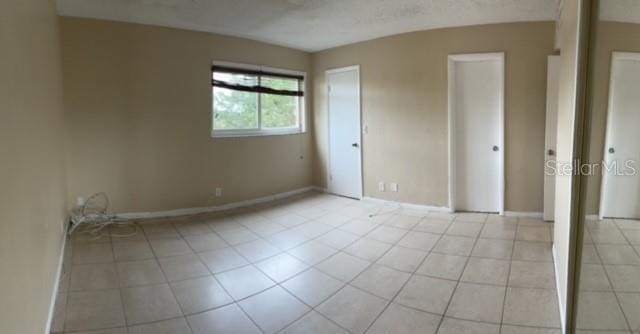 unfurnished bedroom with baseboards and light tile patterned floors