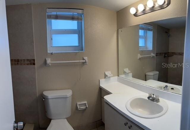full bathroom featuring toilet, walk in shower, and vanity
