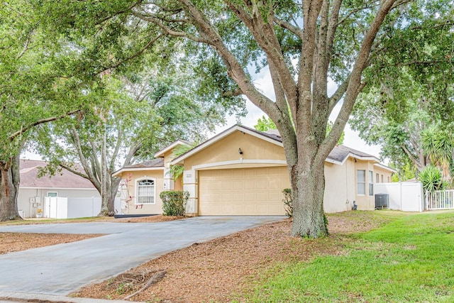ranch-style house featuring an attached garage, driveway, fence, and stucco siding