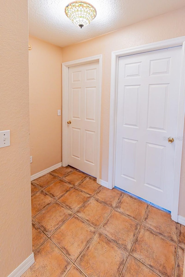 entryway with baseboards, a textured ceiling, and light tile patterned floors