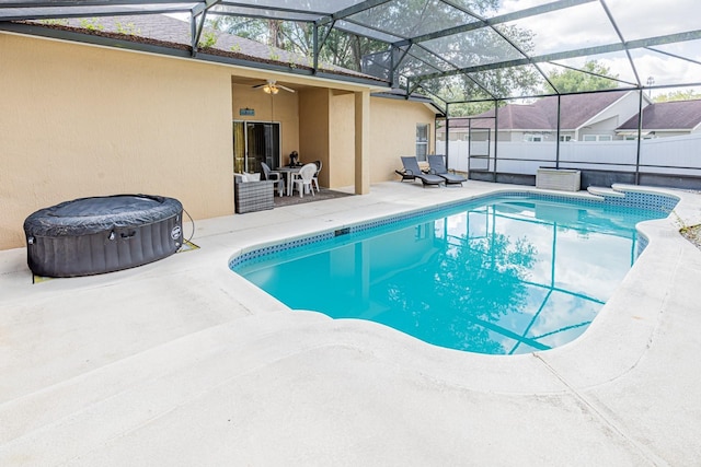 view of pool with glass enclosure, a hot tub, a fenced in pool, a patio, and ceiling fan