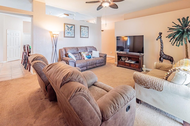 living room featuring baseboards, light colored carpet, ceiling fan, and light tile patterned floors
