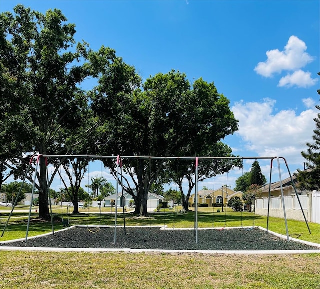 view of property's community featuring a yard, fence, and playground community