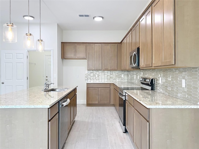 kitchen featuring light stone countertops, decorative backsplash, a sink, and appliances with stainless steel finishes
