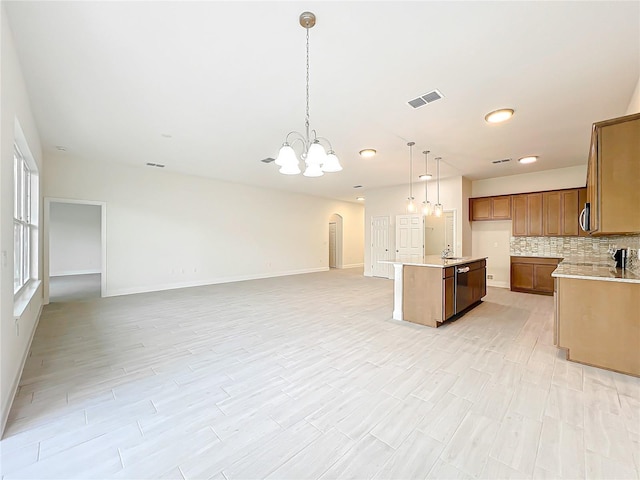 kitchen featuring tasteful backsplash, open floor plan, baseboards, visible vents, and light countertops